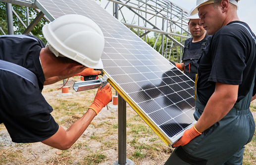 Three men installing solar panel system outdoors.